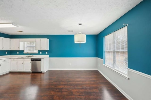 kitchen with dark wood-type flooring, a sink, stainless steel dishwasher, white cabinetry, and light countertops