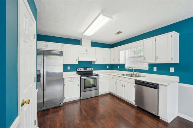 kitchen featuring visible vents, a sink, stainless steel appliances, extractor fan, and white cabinetry