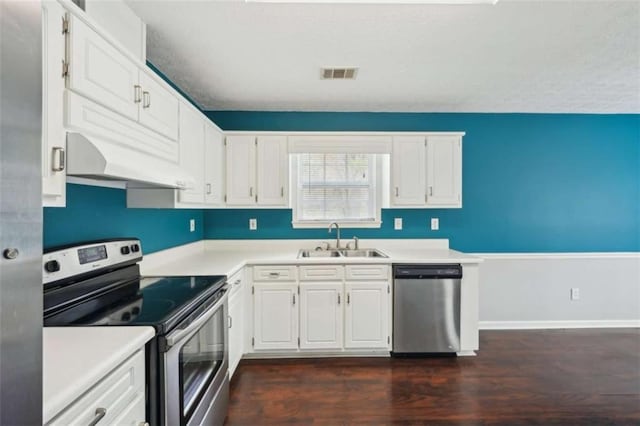 kitchen featuring visible vents, under cabinet range hood, appliances with stainless steel finishes, white cabinets, and a sink