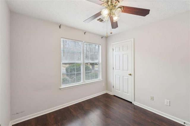 empty room featuring visible vents, baseboards, a ceiling fan, and dark wood-style flooring