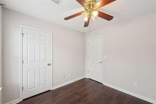 unfurnished bedroom featuring dark wood finished floors, visible vents, baseboards, and ceiling fan