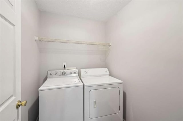 clothes washing area featuring laundry area, washer and dryer, and a textured ceiling