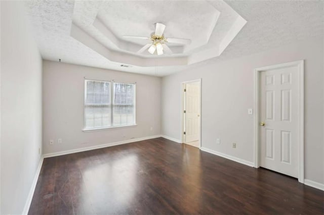 spare room with a tray ceiling, baseboards, a textured ceiling, and wood finished floors