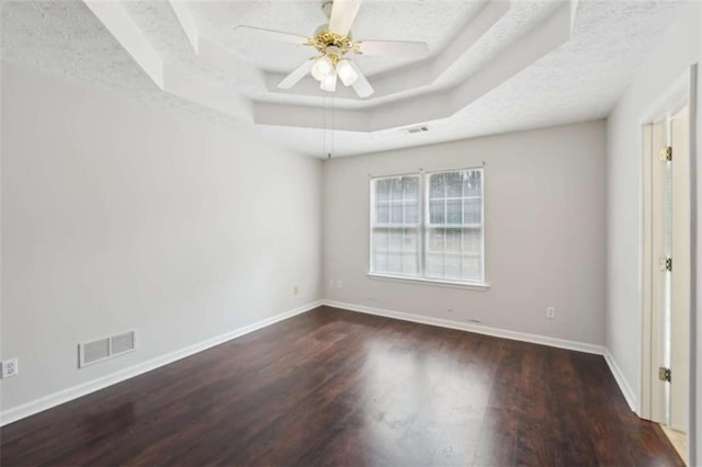 unfurnished room featuring visible vents, a raised ceiling, baseboards, and wood finished floors