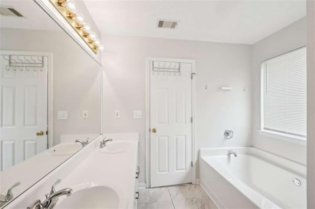 bathroom featuring a bath, visible vents, marble finish floor, and a sink