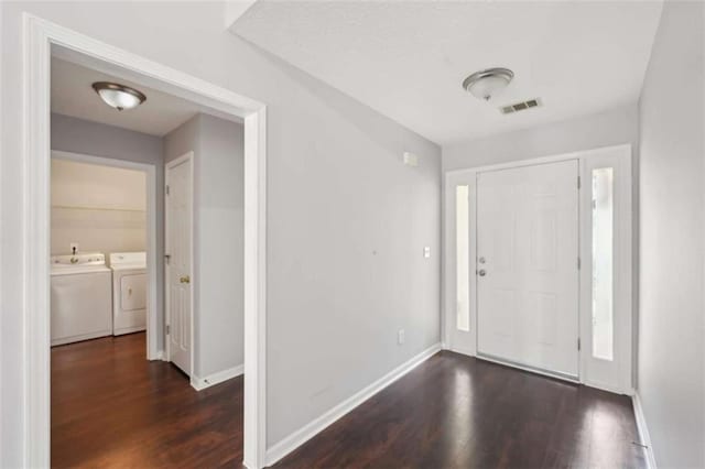 foyer entrance featuring visible vents, wood finished floors, baseboards, and washing machine and dryer