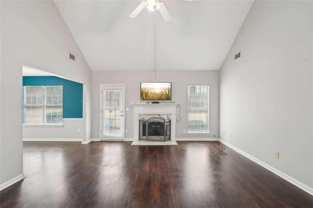 unfurnished living room with wood finished floors, a fireplace with raised hearth, and visible vents