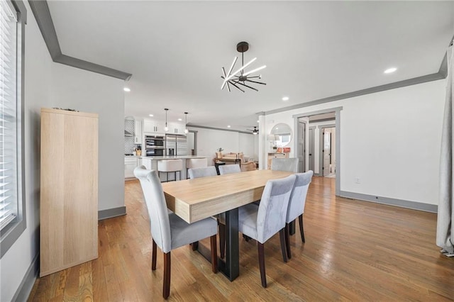 dining space with crown molding, sink, light hardwood / wood-style flooring, and a notable chandelier