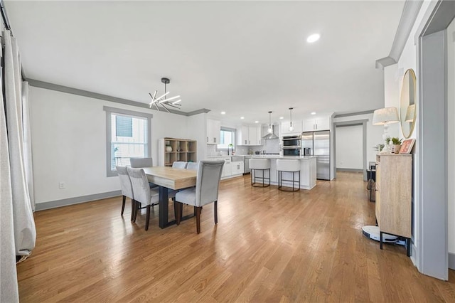 kitchen with wall chimney range hood, hardwood / wood-style flooring, sink, and white cabinets