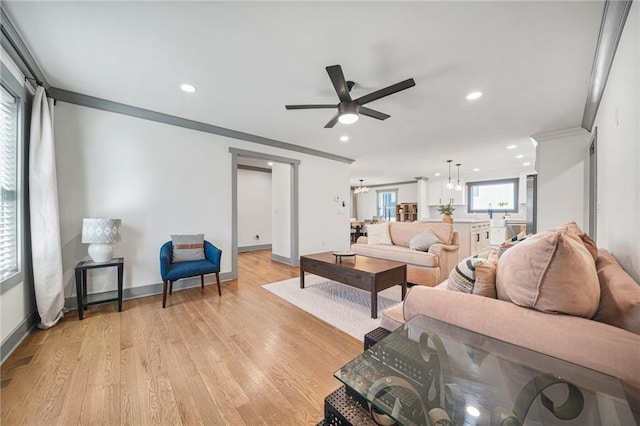 living room featuring crown molding, ceiling fan, and light wood-type flooring