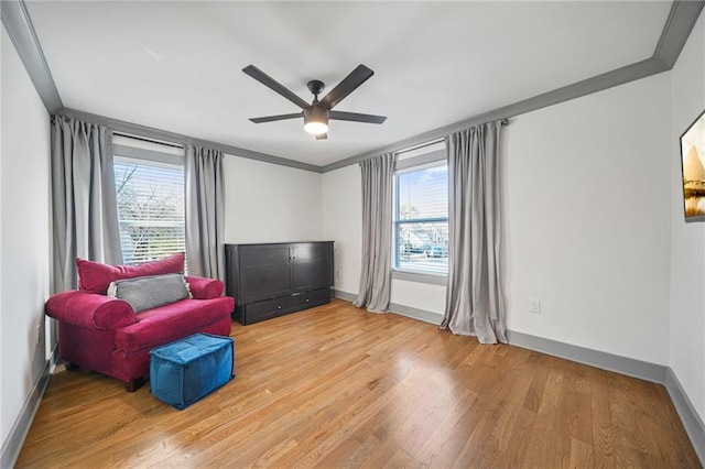 living area featuring ceiling fan, ornamental molding, and light wood-type flooring