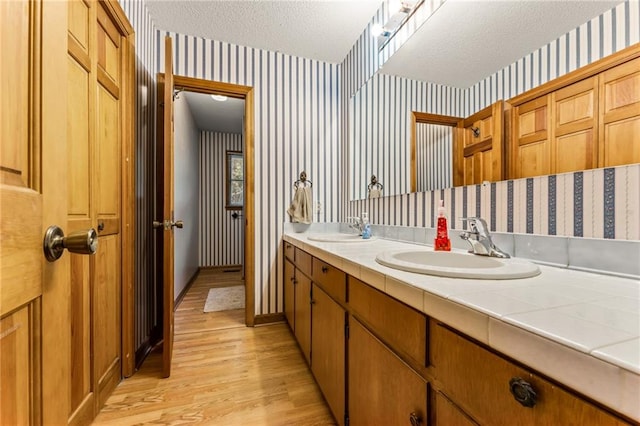 bathroom with a textured ceiling, hardwood / wood-style flooring, and double sink vanity