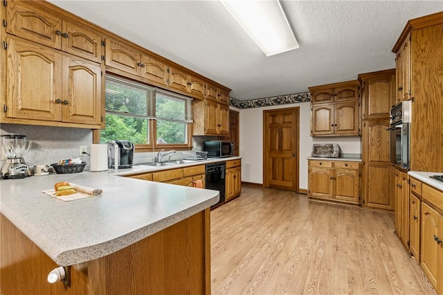 kitchen with sink, appliances with stainless steel finishes, kitchen peninsula, and light hardwood / wood-style flooring