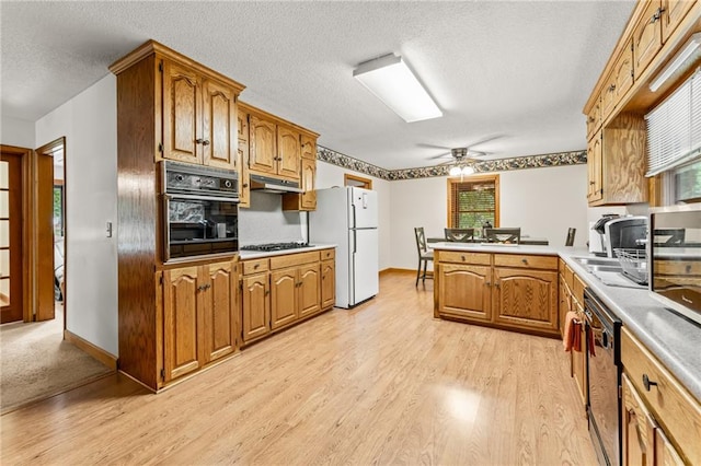 kitchen featuring light hardwood / wood-style floors, black oven, and ceiling fan