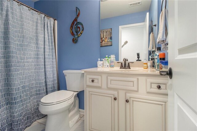 bathroom with tile patterned floors, curtained shower, vanity, and toilet