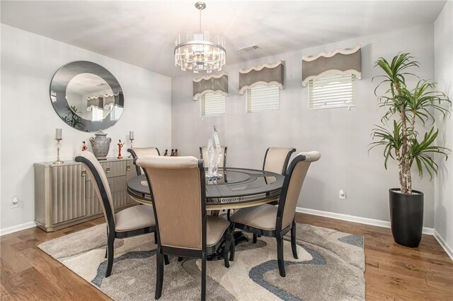 dining area featuring wood-type flooring and an inviting chandelier