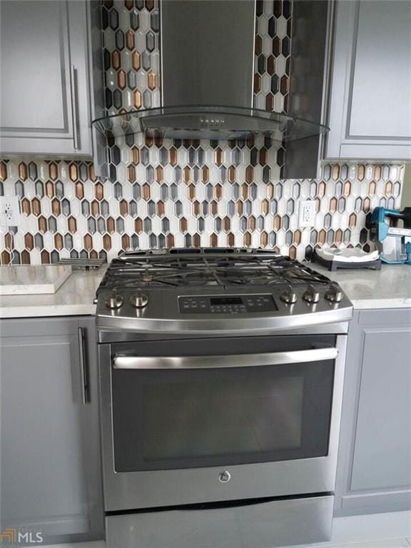 kitchen featuring stainless steel gas range, backsplash, and wall chimney range hood