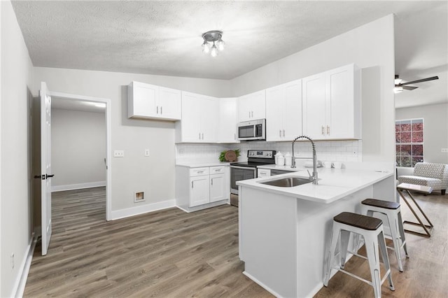 kitchen with sink, stainless steel appliances, dark hardwood / wood-style flooring, a textured ceiling, and white cabinets