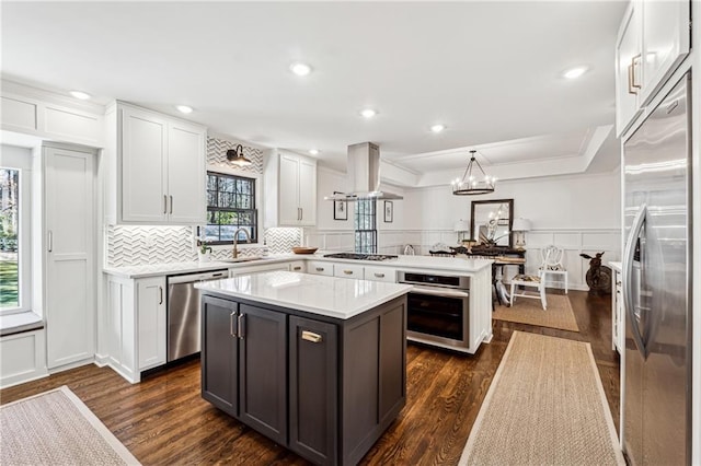 kitchen with light countertops, hanging light fixtures, appliances with stainless steel finishes, a kitchen island, and a peninsula