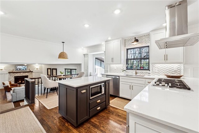 kitchen featuring island range hood, white cabinets, open floor plan, decorative light fixtures, and stainless steel appliances