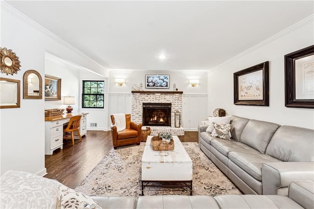 living room with ornamental molding, a brick fireplace, dark wood-style flooring, and visible vents