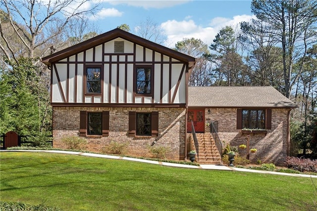 english style home featuring a shingled roof, a front yard, brick siding, and stucco siding