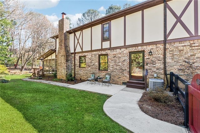 rear view of property featuring brick siding, a chimney, stucco siding, a lawn, and entry steps