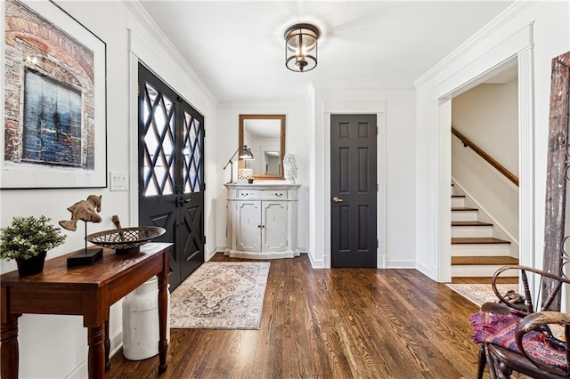 foyer entrance with crown molding, stairs, baseboards, and dark wood-type flooring