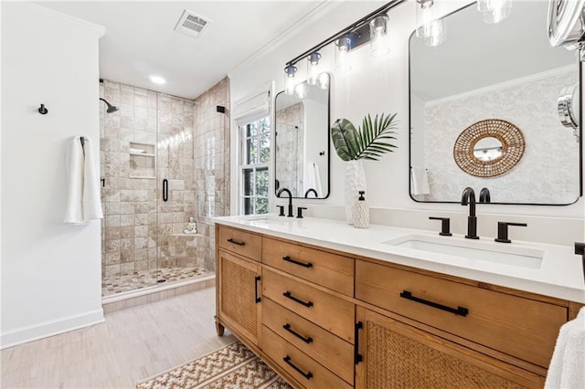 bathroom featuring double vanity, a stall shower, visible vents, ornamental molding, and a sink