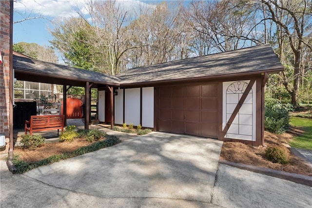 exterior space with a garage, roof with shingles, and driveway