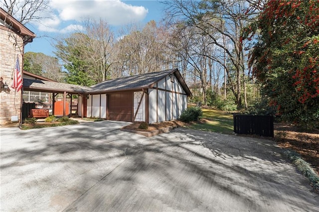 view of side of home featuring an attached garage, driveway, and an outdoor structure