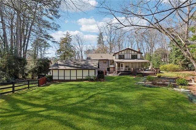 back of property featuring a chimney, fence, a lawn, and a wooden deck