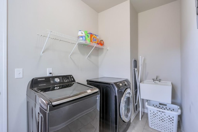 clothes washing area with sink, light tile patterned floors, and washing machine and clothes dryer