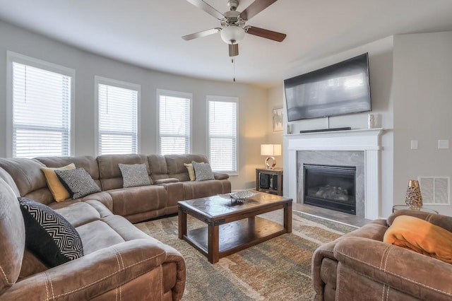 living room with a premium fireplace and ceiling fan