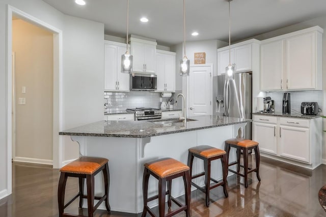 kitchen featuring white cabinetry, sink, dark stone counters, and appliances with stainless steel finishes