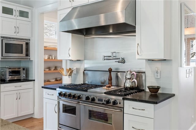 kitchen with white cabinetry, appliances with stainless steel finishes, wall chimney exhaust hood, and a toaster