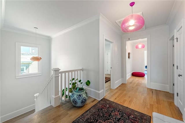 corridor with crown molding, an upstairs landing, baseboards, and light wood finished floors