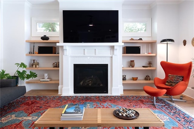 living room with a fireplace with flush hearth, wood finished floors, and ornamental molding