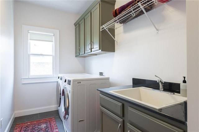 washroom featuring dark tile patterned flooring, a sink, washing machine and dryer, cabinet space, and baseboards