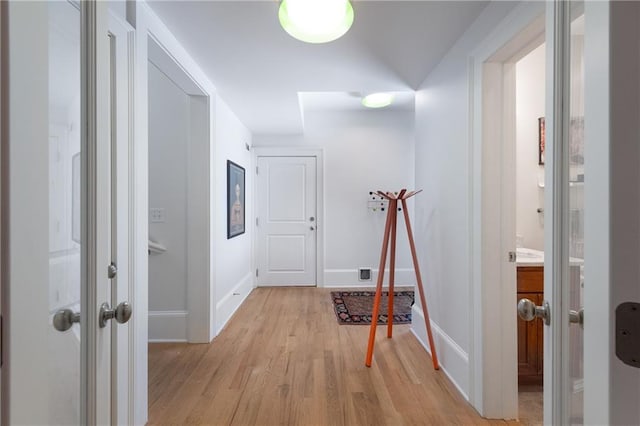 hall with baseboards and light wood finished floors