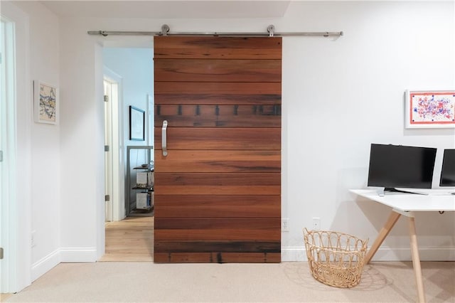 interior space featuring a barn door, wood finished floors, and baseboards