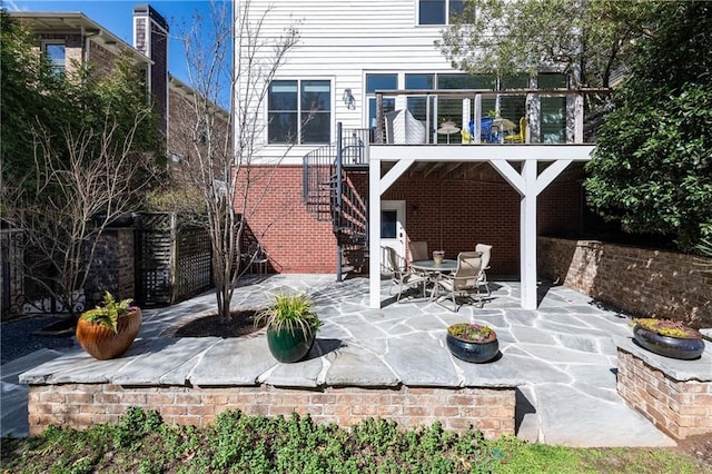 rear view of property with stairs, a patio, and brick siding