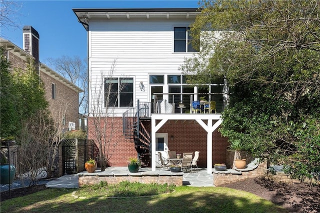 back of house featuring brick siding, stairway, a patio, and fence