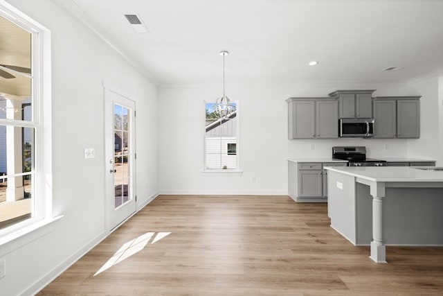 kitchen with gray cabinets, light countertops, an inviting chandelier, appliances with stainless steel finishes, and ornamental molding