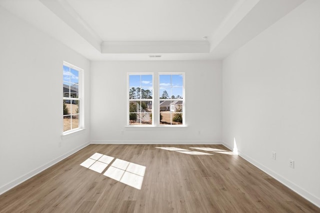 unfurnished room featuring a tray ceiling, baseboards, and wood finished floors