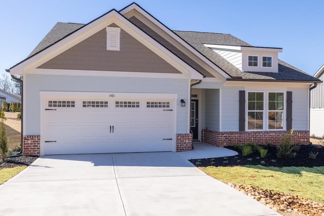 view of front of home featuring a garage, roof with shingles, concrete driveway, and brick siding