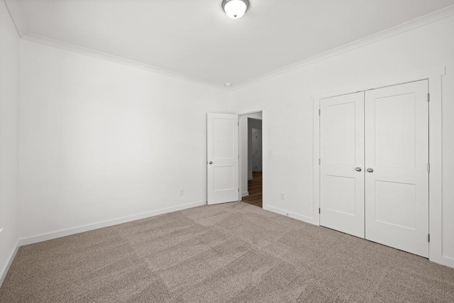 unfurnished bedroom with carpet, a closet, ornamental molding, and baseboards