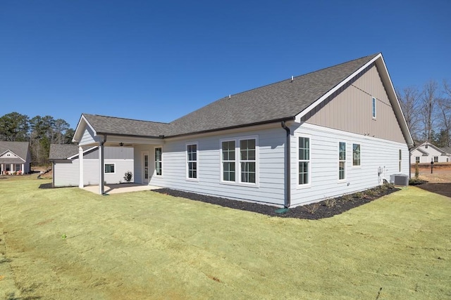 back of house with a shingled roof, a ceiling fan, a lawn, a patio, and cooling unit