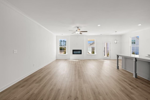 unfurnished living room featuring light wood-type flooring, a fireplace, baseboards, and ceiling fan with notable chandelier