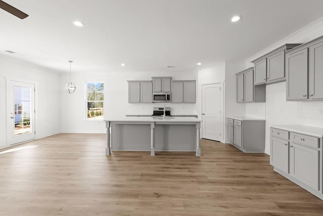 kitchen featuring recessed lighting, stainless steel microwave, light wood-style flooring, and gray cabinetry